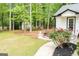 Landscaped backyard featuring a well-maintained lawn, mature trees, and patio area, adjacent to a white house at 909 Ne Otter Way Ne Way, Marietta, GA 30068