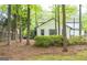 Rear exterior view of a white house with black trim, surrounded by trees, greenery, and a manicured lawn at 909 Ne Otter Way Ne Way, Marietta, GA 30068