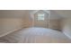Unfinished attic space showcasing neutral walls, plush carpeting, and a single window for natural light at 1555 New Ne St, Atlanta, GA 30307
