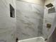 Close up on a shower with marble tiling, gold hardware and a shower niche for storage at 2148 M L King Jr Sw Dr, Atlanta, GA 30310