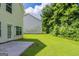 View of the backyard with grass and shrubbery, a concrete patio, and the siding on the rear of the house at 513 Shadow Valley Ct, Lithonia, GA 30058