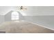 Bright attic space with neutral walls, ceiling fan, and arched window overlooking neighborhood at 950 Besse Way, Locust Grove, GA 30248