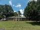 Charming single-story brick home featuring a green metal roof, blue shutters, and mature trees on a spacious lawn at 1253 Gatewood Drive Dr, Lawrenceville, GA 30043