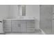 Modern bathroom featuring gray cabinets, dual sinks, and a glass-enclosed shower at 3893 Indian Shoals Road, Dacula, GA 30019