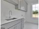 Bright laundry room with gray cabinets, white countertops, a stainless steel sink, and outside view at 3893 Indian Shoals Road, Dacula, GA 30019
