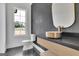 Modern powder room with gold sink, gray accent wall, black patterned floors, and outside view at 3893 Indian Shoals Road, Dacula, GA 30019