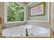 Bright soaking tub with tile surround and picture window provides perfect relaxation space at 1788 River Bluff Vw, Duluth, GA 30097