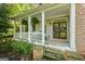 Inviting front porch with white columns, a cozy seating area, and lush greenery, perfect for relaxing outdoors at 1788 River Bluff Vw, Duluth, GA 30097