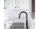 Sleek kitchen featuring matte black plumbing fixture, stainless steel sink, and marble backsplash at 6127 Landers Loop, Fairburn, GA 30213