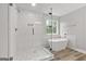 Bright bathroom featuring a walk-in shower, a soaking tub, and a window with a backyard view at 5341 Stewart Mill Rd, Douglasville, GA 30135