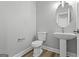 Compact half bath featuring a pedestal sink, toilet, and modern fixtures at 5341 Stewart Mill Rd, Douglasville, GA 30135
