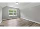 A simple, unfinished bedroom with neutral paint and trim, plank floors, and a view of trees outside at 5341 Stewart Mill Rd, Douglasville, GA 30135