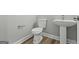 Modern powder room with a pedestal sink, white toilet, and wood-look vinyl plank flooring at 5341 Stewart Mill Rd, Douglasville, GA 30135