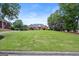 Well-maintained front yard with a large lawn, mature trees, and a brick home with a dark roof at 411 Hickory Fairway Ct, Woodstock, GA 30188