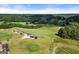 Aerial view of the golf course with golf carts, green lawns, and red buildings at 411 Hickory Fairway Ct, Woodstock, GA 30188