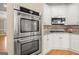 Kitchen with stainless steel double oven and microwave, complemented by white cabinets and granite countertops at 411 Hickory Fairway Ct, Woodstock, GA 30188