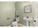 Charming powder room featuring a pedestal sink, toilet, and decorative artwork at 411 Hickory Fairway Ct, Woodstock, GA 30188