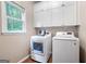 Bright laundry room with white cabinetry, modern appliances, and a window providing natural light at 5418 Amity Dr, Powder Springs, GA 30127