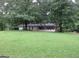 Quaint single-story home with a lush green lawn and mature trees creating a serene, private setting at 125 Highland Cir, Stockbridge, GA 30281