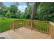 An outdoor wooden deck with wooden railing overlooks a grassy lawn shaded by mature trees at 4451 Flat Shoals, Decatur, GA 30034