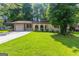 Charming single-story home with a lush green lawn, attached garage, and inviting arched entryway at 1105 Buckhurst Dr, Atlanta, GA 30349