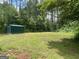 Large backyard with lush green lawn and a storage shed surrounded by mature trees at 176 Avalon Way, Riverdale, GA 30274
