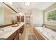 Bright bathroom featuring a jacuzzi tub, a glass-enclosed shower, and a double sink vanity with dark wood cabinets at 826 Richmond Cir, Peachtree City, GA 30269