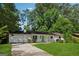 Single-story home has a white exterior, attached garage, and lush landscaping at 3123 Deshong Dr, Stone Mountain, GA 30087