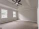 Spacious carpeted main bedroom featuring tray ceilings, a ceiling fan and large windows at 5674 Mountain Cres, Stone Mountain, GA 30087