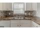 Close-up of the kitchen sink area, featuring stainless steel sink and mosaic backsplash at 1006 Eagle Vw, Lawrenceville, GA 30044