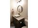 Stylish bathroom with marble countertop vanity, round mirror, and wood laminate flooring at 11940 Wexford Club Dr, Roswell, GA 30075