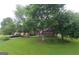 Well-maintained home exterior featuring lush lawn, mature trees, and a circular driveway at 11940 Wexford Club Dr, Roswell, GA 30075