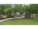 Beautifully landscaped front yard with lush grass and mature trees framing the brick home and driveway at 11940 Wexford Club Dr, Roswell, GA 30075