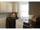 Well-lit laundry room showcasing modern black Samsung washer and dryer units and overhead white cabinets at 11940 Wexford Club Dr, Roswell, GA 30075