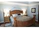 Light-filled main bedroom boasts a large wooden bed frame, neutral decor, and hardwood flooring at 11940 Wexford Club Dr, Roswell, GA 30075