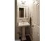 Elegant powder room with decorative wallpaper, pedestal sink, and a framed mirror at 11940 Wexford Club Dr, Roswell, GA 30075