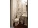 Charming powder room with stylish wallpaper, pedestal sink, and decorative mirror at 11940 Wexford Club Dr, Roswell, GA 30075