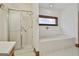 Bathroom with white tiled floors, a walk-in shower, and a soaking tub under a window at 936 Bo Bo Banks Rd, Grantville, GA 30220