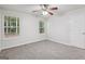 Carpeted bedroom with ceiling fan and a pair of windows overlooking green foliage at 1528 Wembley Dr, Douglasville, GA 30134