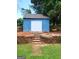 The blue shed features white doors and sits atop a tiered retaining wall with stone steps on a manicured lawn at 2913 Jordan Forest Trail, Lawrenceville, GA 30044
