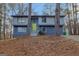 Two-story home with blue siding, a bright green door, and mature trees in a wooded setting at 4064 Chimney Ridge Way, Ellenwood, GA 30294