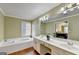 Bright bathroom features a soaking tub, double sinks, white cabinets, and wood floors at 3034 Brookgreen Trl, Lawrenceville, GA 30043