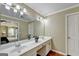 Bright bathroom featuring double sinks, white cabinets, and a large mirror reflecting a view into the bedroom at 3034 Brookgreen Trl, Lawrenceville, GA 30043