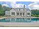 Stunning backyard featuring a sparkling pool with lounge area, set against a beautifully designed white farmhouse at 5187 Lower Fayetteville Rd, Sharpsburg, GA 30277