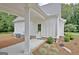Covered patio of a home with vertical siding, brick accents, and manicured landscaping around the side entry door at 5187 Lower Fayetteville Rd, Sharpsburg, GA 30277