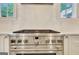Close-up of a kitchen gas range with stainless steel hood and light filled windows at 5187 Lower Fayetteville Rd, Sharpsburg, GA 30277
