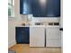Bright laundry room boasts navy cabinets, white front loading washer and dryer, and light wood floors at 5187 Lower Fayetteville Rd, Sharpsburg, GA 30277