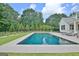 Lovely backyard pool surrounded by lush greenery and the beautiful architecture of a modern farmhouse at 5187 Lower Fayetteville Rd, Sharpsburg, GA 30277