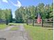 Property entrance with dark wooden fence, gravel driveway, and American flag at 5187 Lower Fayetteville Rd, Sharpsburg, GA 30277