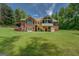 Expansive backyard features a two-story brick home, wooden deck and stairs, lush lawn, and mature trees for privacy at 1041 Flat Rock Rd, Covington, GA 30014